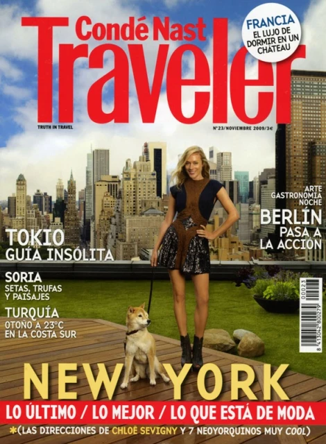 Condé Nast Traveler magazine cover featuring a model in a black dress with a Shiba Inu, set against a backdrop of New York City buildings.