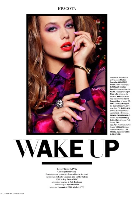 Blonde woman poses in floral top, her hand near her face. She has purple eyeshadow and red lipstick in a beauty fashion shot.