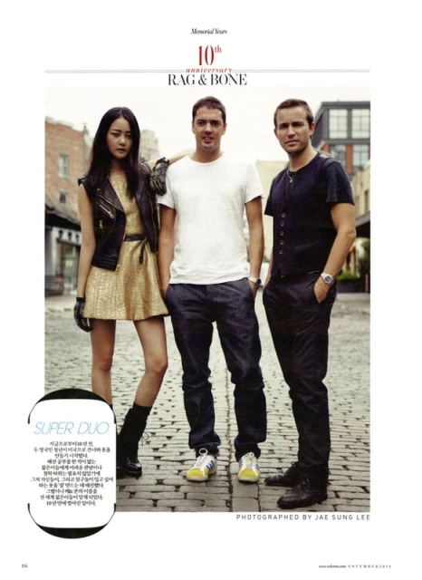 Fashion editorial photo with three people standing on a brick street: an Asian woman in a gold dress and two Caucasian men.