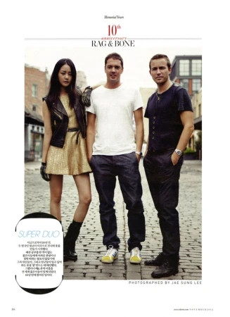Fashion editorial photo with three people standing on a brick street: an Asian woman in a gold dress and two Caucasian men.