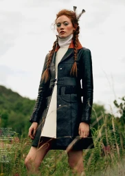 Red-haired model in a black leather coat with braided hair standing in an outdoor meadow in Los Angeles.
