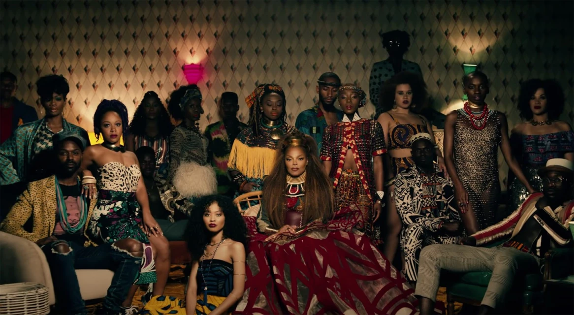 A large group of people in a room, mostly African Americans, wearing traditional African patterns and fabrics, posing for a portrait.