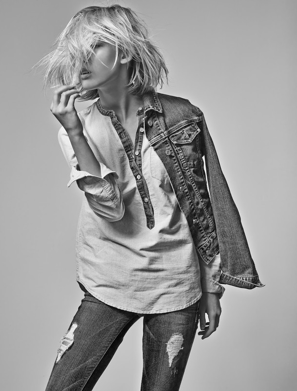 Black and white portrait of a blonde woman wearing distressed jeans, button-up shirt, and denim jacket