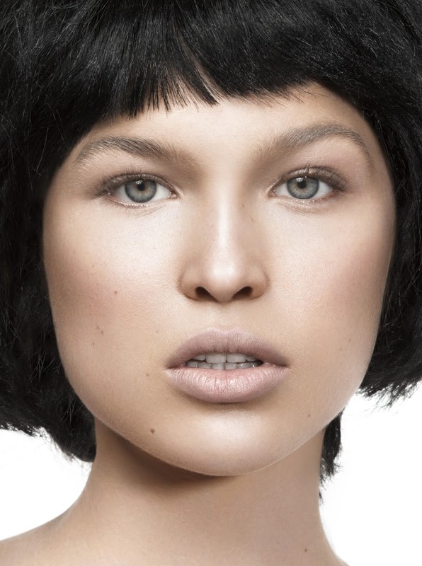 Close-up portrait of a young adult female with short dark hair, light skin, and grey eyes, posing in a photo studio with a white backdrop.
