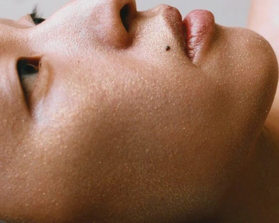 Close-up beauty portrait of a person profile with golden glitter makeup on skin by Jen Fiamengo