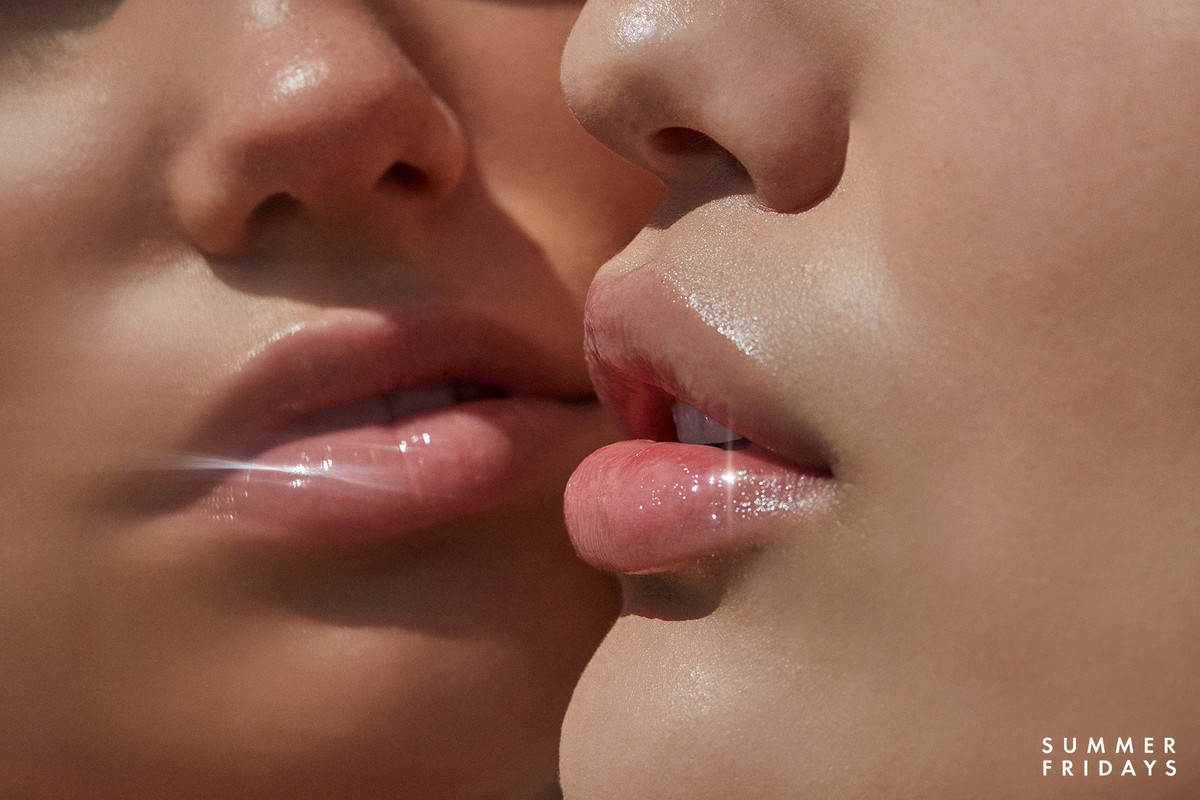 Close-up of two adult female faces with glossy lips and soft skin, featuring cosmetic product and skincare brand SUMMER FRIDAYS.
