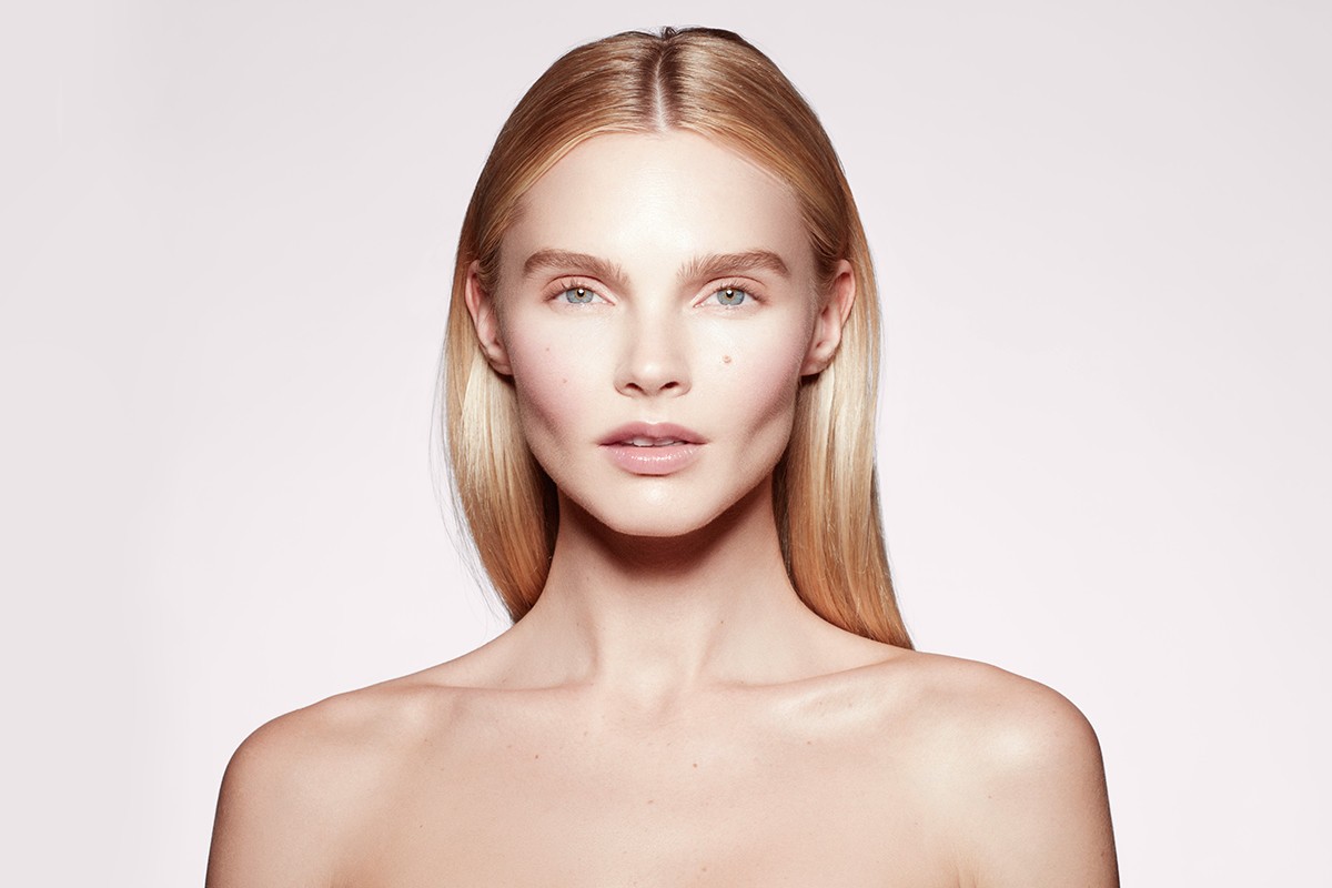 Portrait of a blonde woman with fair skin in a beauty shot with a neutral expression in a studio environment against a white background.