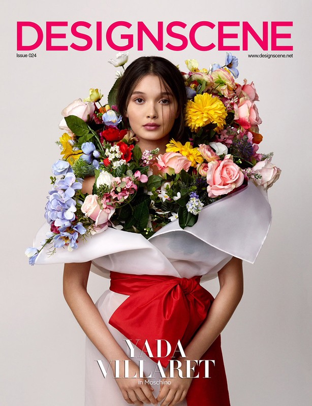 Young woman poses in a fashion magazine cover photo, adorned with vibrant flowers, wearing a dress with a bold red bow around the waist.