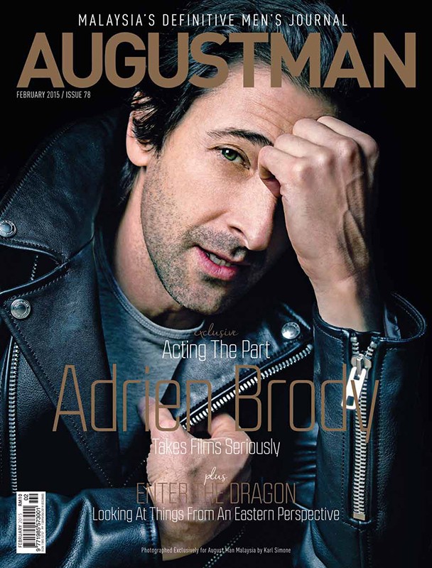 AugustMan magazine cover featuring a close-up portrait of actor Adrien Brody in a leather jacket, with magazine text overlays and dark background.