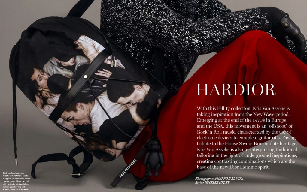 Black backpack with a group of men printed on it, accented by a stylish red trouser and black patterned jacket in a fashion editorial.