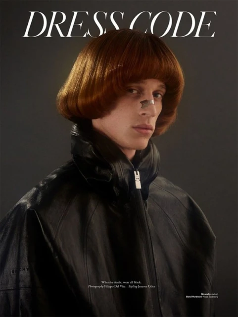 Fashion portrait of a young adult with an auburn bob haircut, wearing a black leather jacket against a dark grey background in a magazine cover.