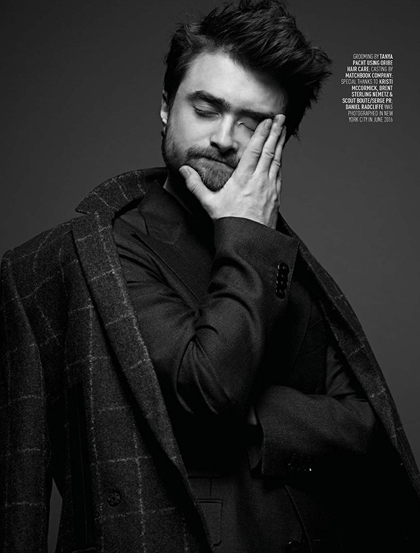 Black and white portrait of a man with dark hair and a beard, wearing a suit and an overcoat, with his hand near his face.