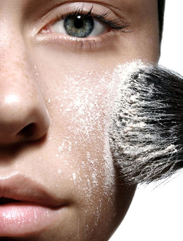 Close-up of a woman's face with fair skin as makeup powder is applied with a brush, enhancing her features in a beauty shot.