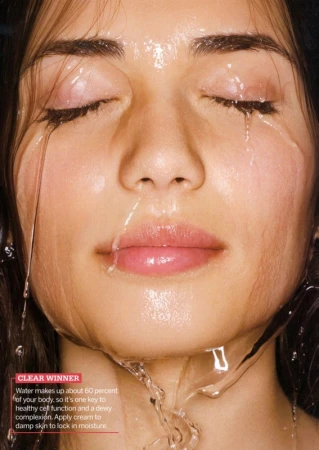 Close-up portrait of a woman with wet skin and closed eyes, water streaming down her face.