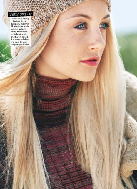 Portrait of a young woman with blonde hair wearing a beanie hat and turtleneck sweater, outdoors in soft, natural light.