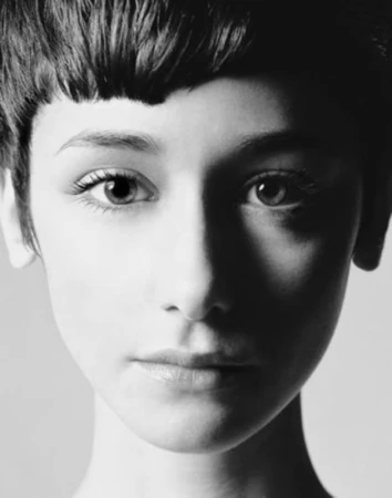 Close-up black and white portrait of a woman with short dark hair and high-contrast lighting.