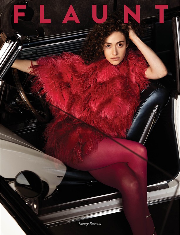 Emmy Rossum poses inside of a car wearing a red faux fur coat and red tights for a magazine cover shoot.