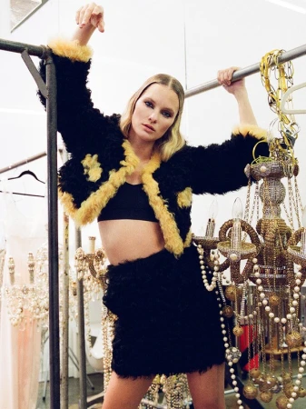 Model in black fuzzy jacket with yellow trim posing in a backstage dressing room by Jennifer Covington-bowers