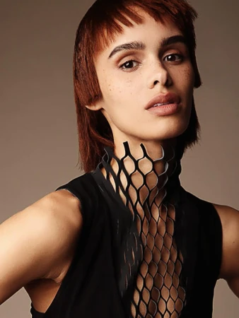 Portrait of a woman with short auburn hair and a black patterned top against a neutral background. Beauty and fashion concept.