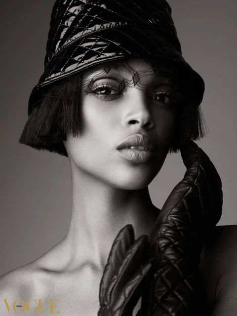Close-up black and white studio shot of a Black female fashion model wearing a quilted hat, black gloves, and editorial makeup.