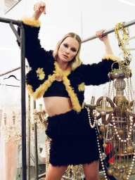 Model in black fuzzy jacket with yellow trim posing in a backstage dressing room by Jennifer Covington-bowers