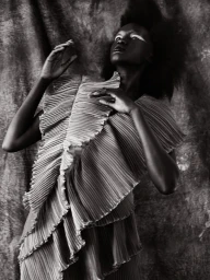 Black and white editorial portrait of a woman in a pleated textured top against a textured background by Jennifer Covington-bowers