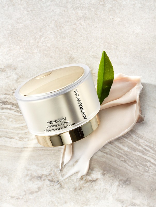 Amorepacific skincare product jar on a marble surface with a leaf and cream, photographed in a soft, studio setting.