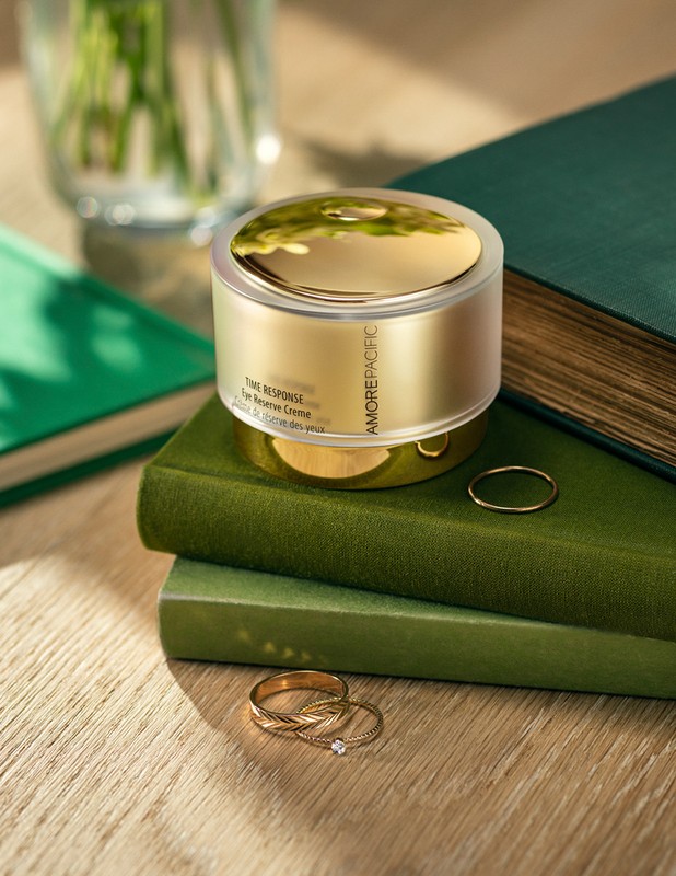 Amorepacific skincare product jar on stacked books in a warm-lit setting showcasing a cosmetic product in an elegant presentation.