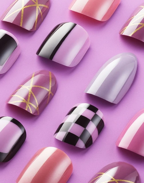Overhead shot of various colorful and patterned artificial nails on a solid lilac background, showcasing salon-style nail art.