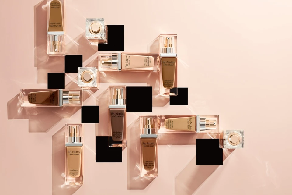 Cosmetic product photography featuring Estée Lauder Re-Nutriv foundation bottles and compacts arranged on transparent acrylic pedestals.