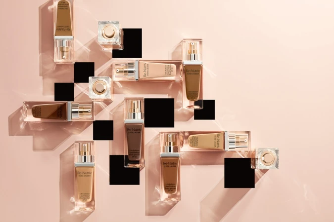 Cosmetic product photography featuring Estée Lauder Re-Nutriv foundation bottles and compacts arranged on transparent acrylic pedestals.