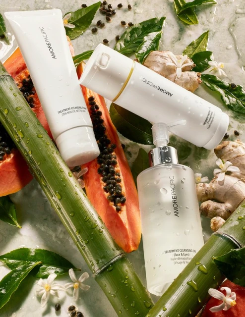 Amorepacific cleansing products sit amongst greenery and fruit, presenting a visually appealing display of skincare and natural elements.
