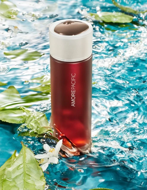 Amorepacific skincare product presented in water with floating leaves and flowers, capturing a serene and fresh beauty essence.