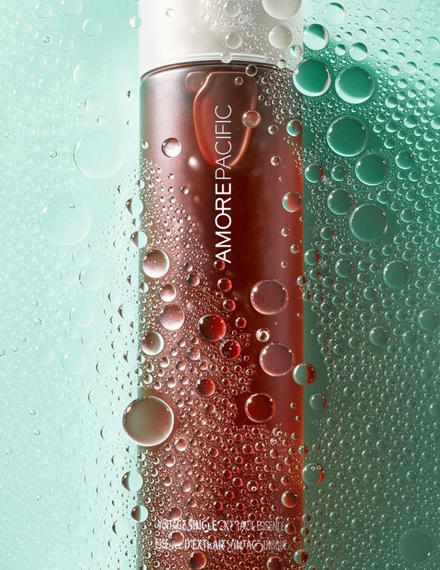 Amorepacific skincare product bottle close-up with water droplets against a soft green background, promoting beauty and skincare.