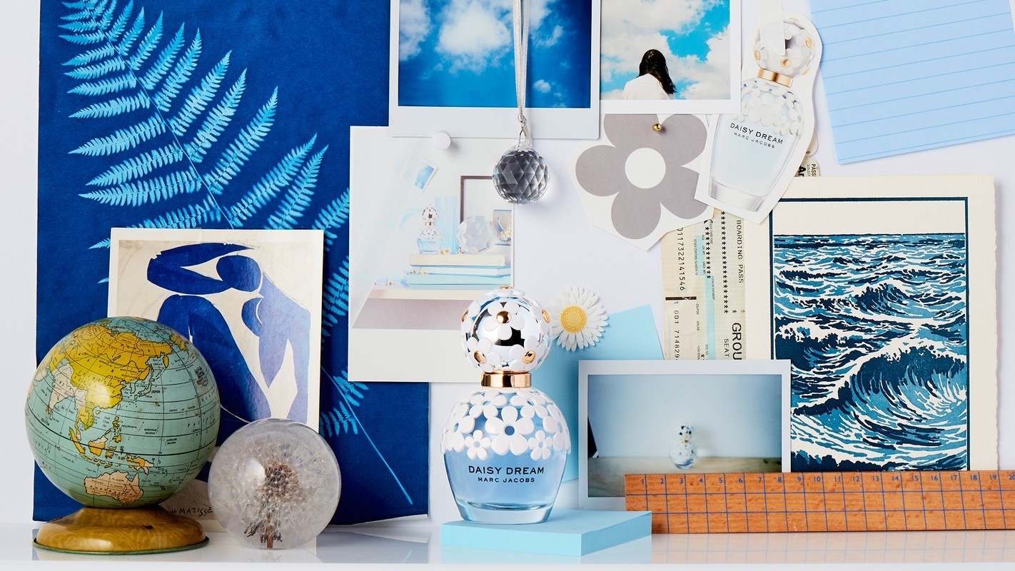 Still life composition featuring a perfume bottle, globe, and artistic elements in a studio setting with cool, calming color palette.