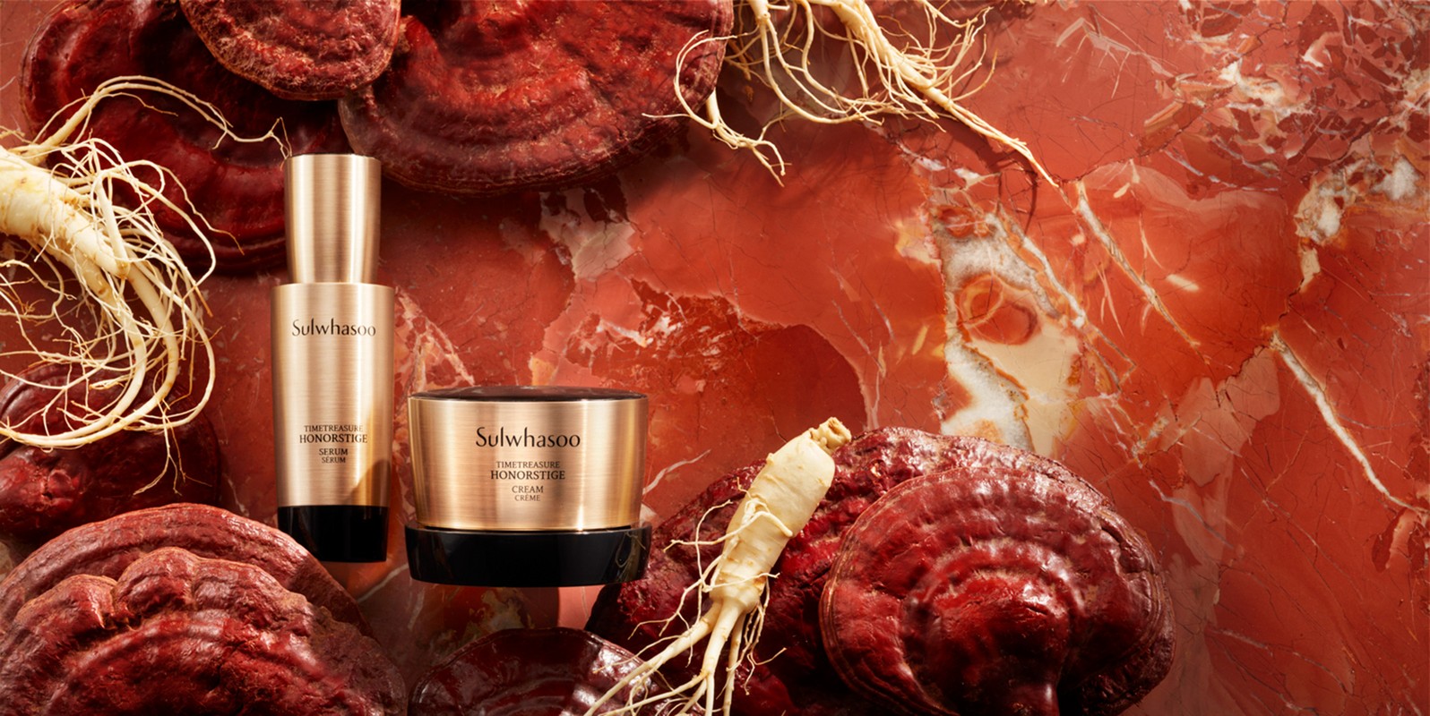 Two Sulwhasoo TimeTreasure Honorstige cream and serum products nestled amongst red reishi mushrooms and ginseng roots against red marble.
