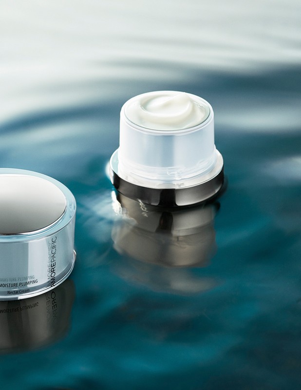 Elevated view of two moisturizing skincare product containers with white cream against a textured teal background.