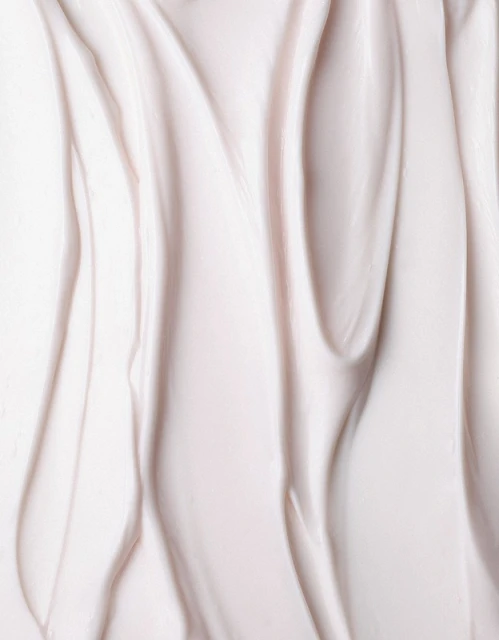 Close-up of rippled, light pink beauty cream filling the frame, showcasing a smooth, soft texture and subtle color variations.
