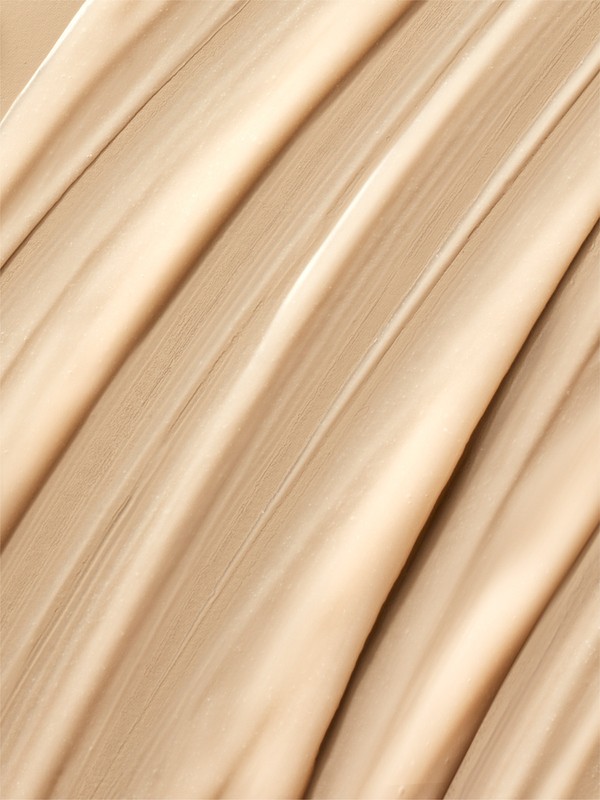 Close-up of smooth beige liquid foundation swatched in diagonal strokes, highlighting a creamy texture and matte finish.