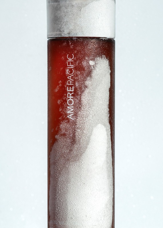 Close-up studio shot of AmorePacific skincare product with white condensation against a bright gradient background.