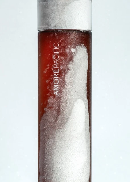 Close-up studio shot of AmorePacific skincare product with white condensation against a bright gradient background.