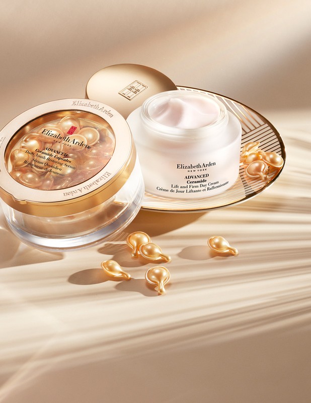 Still life shot of Elizabeth Arden skincare products including Advanced Ceramide capsules and Lift and Firm Day Cream on a neutral surface.