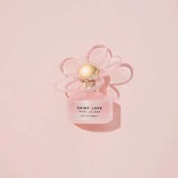 Overhead product shot of a pink Marc Jacobs Daisy Love perfume bottle with a flower cap on a matching pink background.