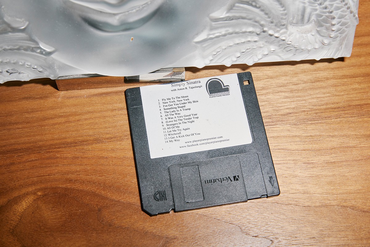 Floppy disk featuring album art for Simply Sinatra with Anton B. Tajanlangh, placed on a wooden surface next to an abstract sculpture.