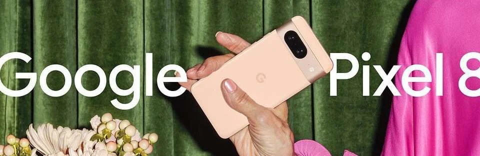 Hand holds Google Pixel 8 phone in front of green textured backdrop with floral arrangement and pink textile. Modern phone promotion.