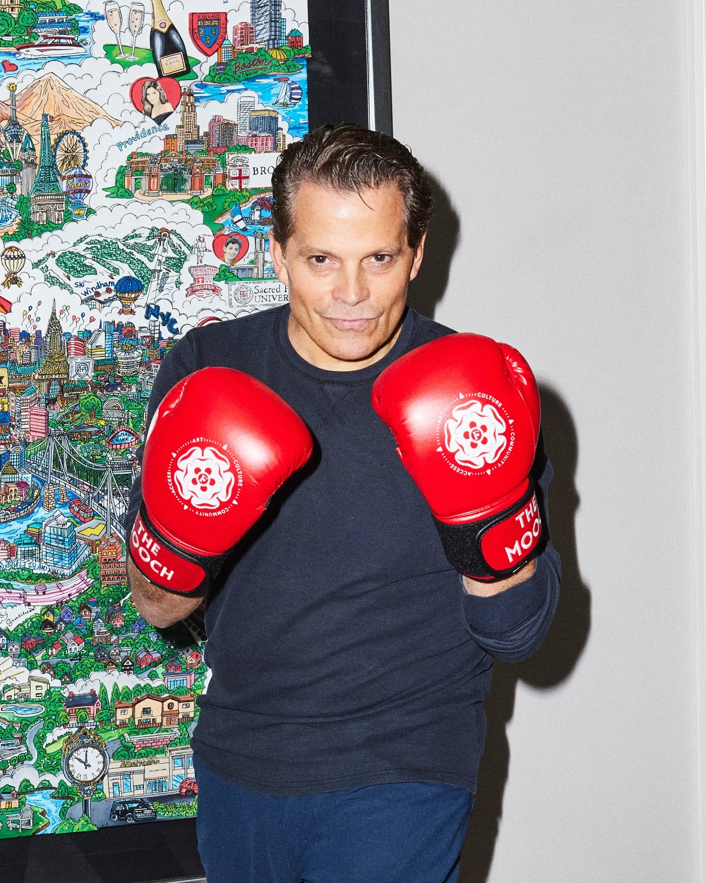 Adult male wearing red boxing gloves posing indoors against a colorful wall art, showcasing a fitness and lifestyle theme.