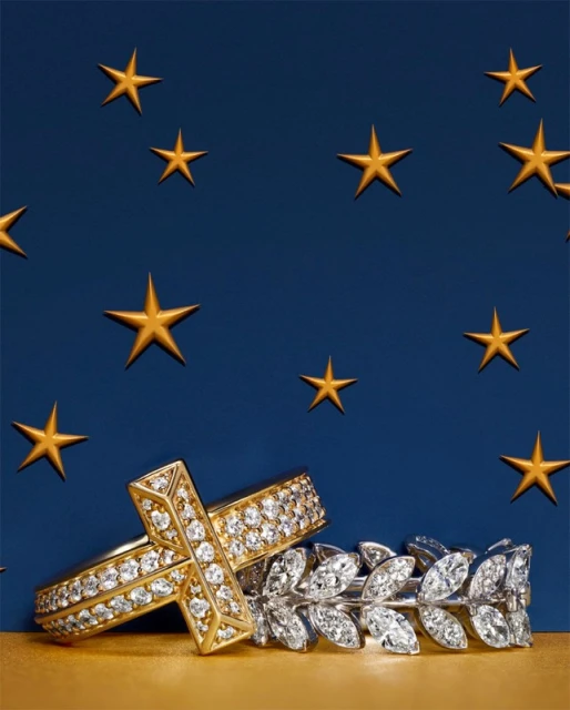 Elegant jewelry still life featuring two diamond rings against a gradient blue and gold background with star-shaped accents. 