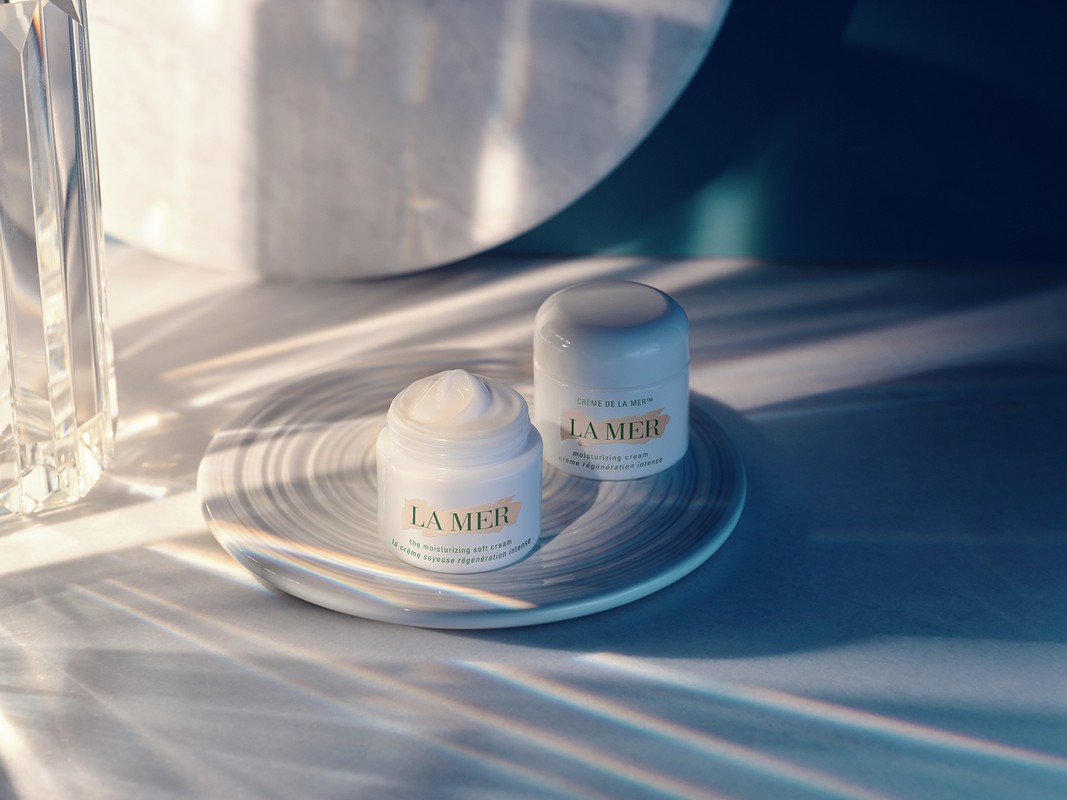 Two La Mer moisturizing cream jars displayed on a marble surface, illuminated by soft, diffused light in a beauty shot.