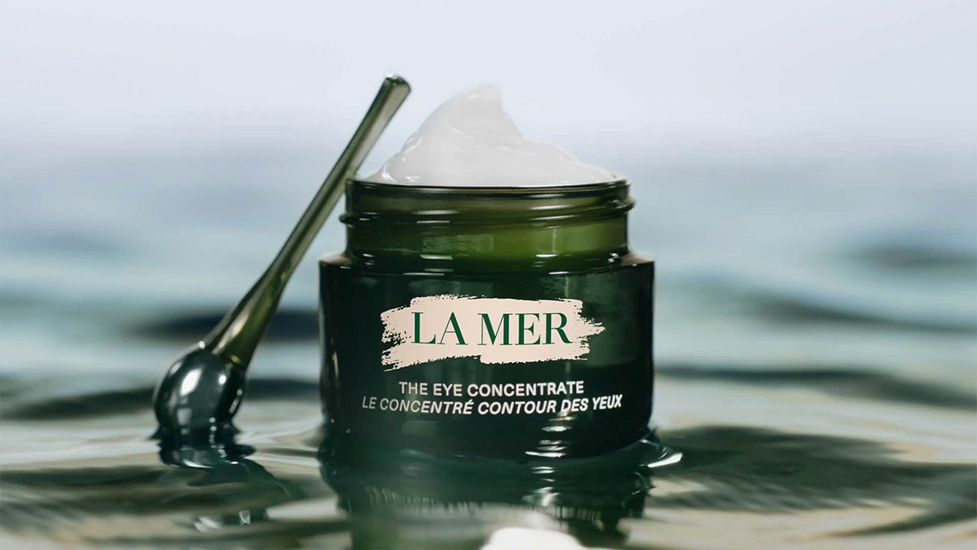 La Mer eye concentrate jar with applicator on rippled water surface, product shot, luxurious skincare brand.