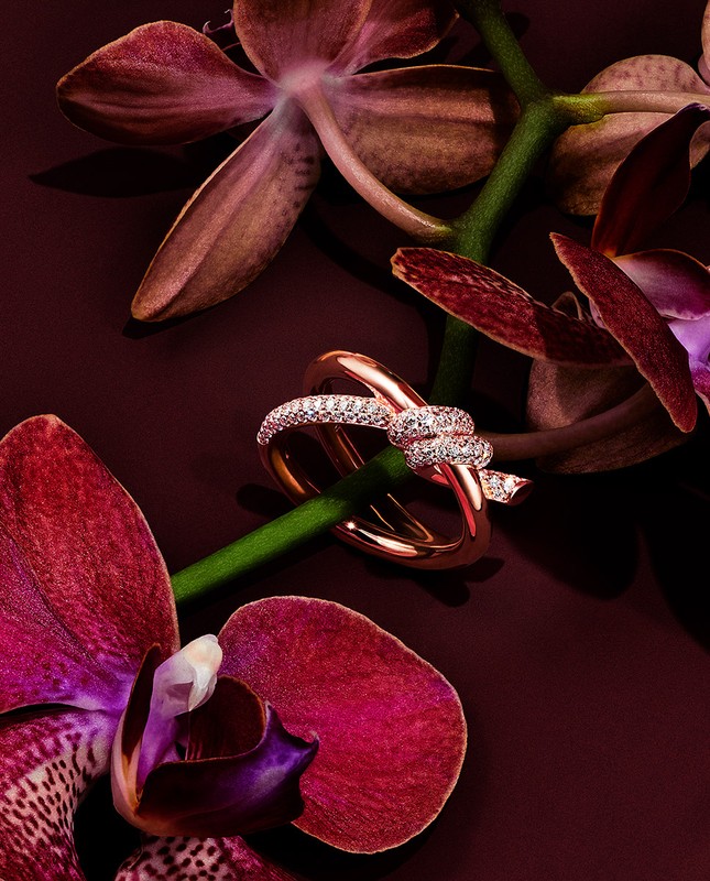 Elegant rose gold ring adorned with diamonds set against vibrant magenta orchids, creating a luxurious and romantic jewelry still life.